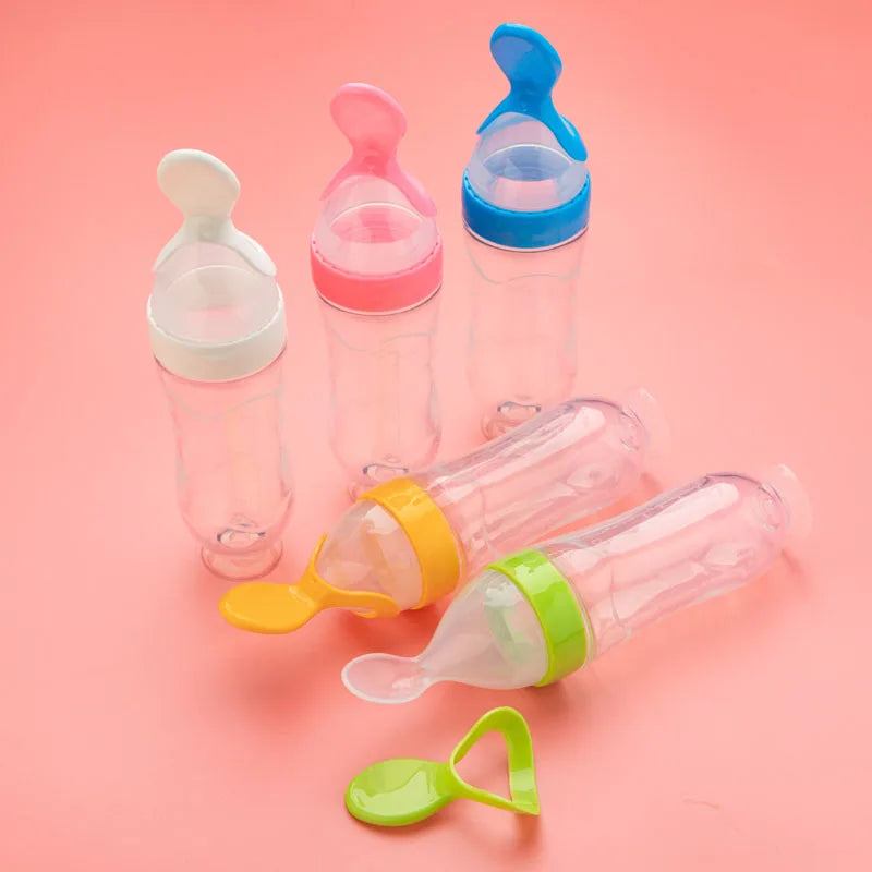 Colorful baby feeding bottles on a pink background