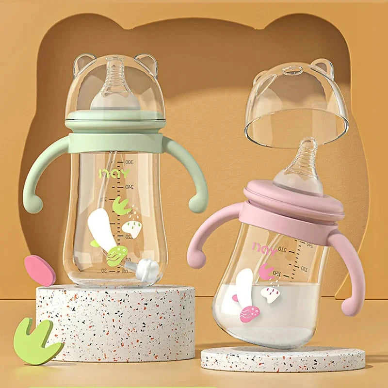 Two baby bottles with green and pink handles on a beige background