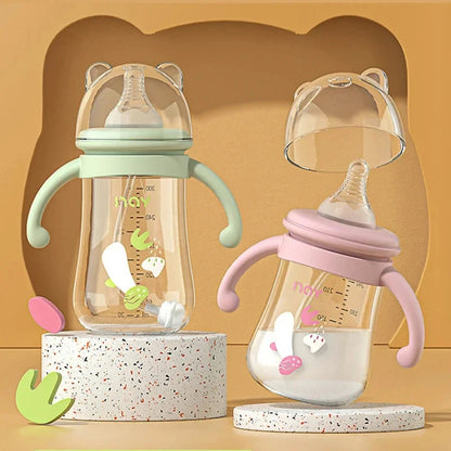 Two baby bottles with green and pink handles on a beige background