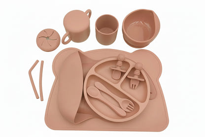 Orange-colored children's tableware set with plate, cups, and cutlery on a white background.