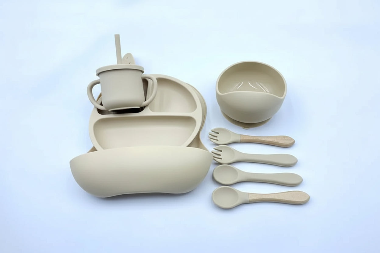 Beige children's dining set with cup, bowl, plate, and utensils on a light blue background.