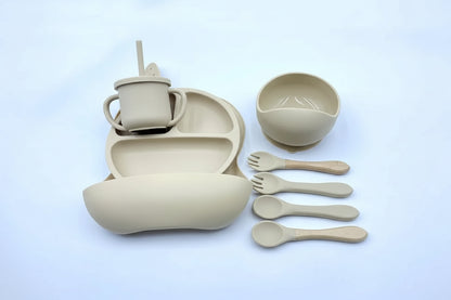 Beige children's dining set with cup, bowl, plate, and utensils on a light blue background.