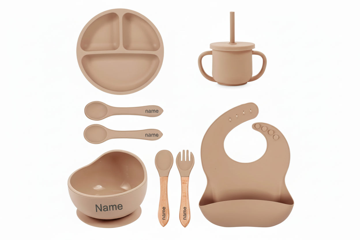Set of brown baby utensils including plate, cup, bowl, spoons, and bib with customizable name or logo.