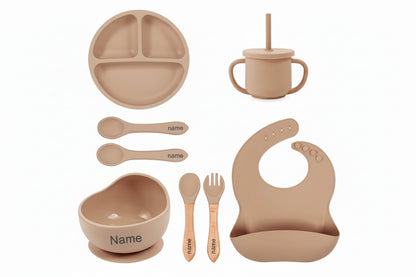 Set of brown baby utensils including plate, cup, bowl, spoons, and bib with customizable name or logo.