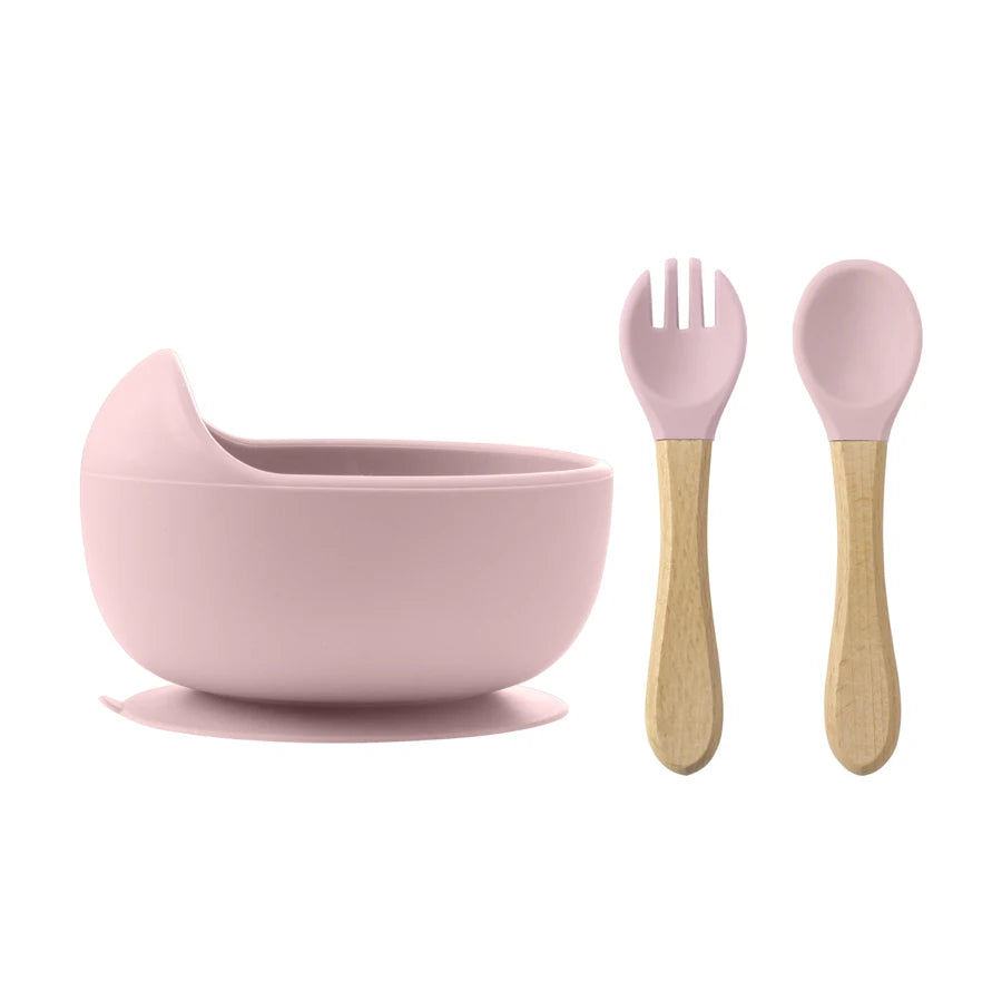 Pink children's bowl, fork, and spoon set on a white background