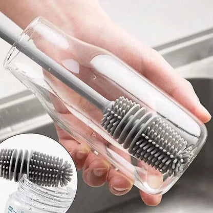 Hand holding a clear plastic bottle with a gray brush inside, against a neutral background.