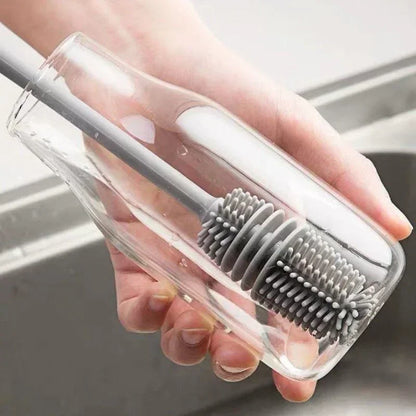 Hand holding a clear plastic brush with bristles over a sink