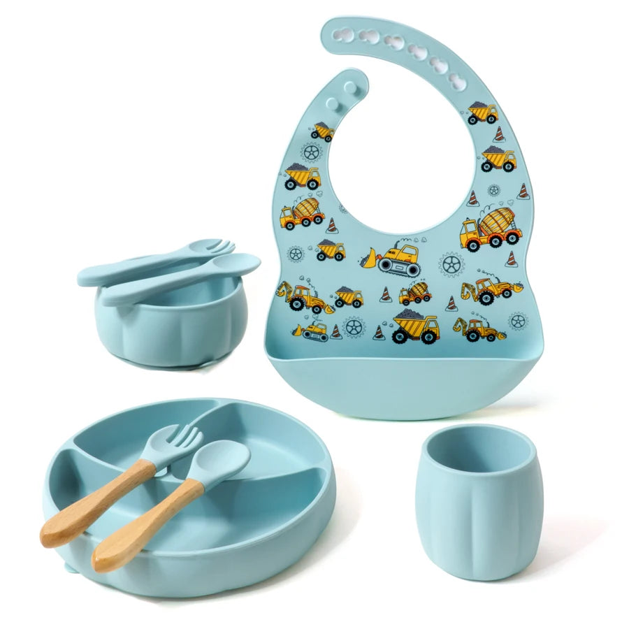 Children's dining set with blue bib, bowl, cup, and utensils on a white background