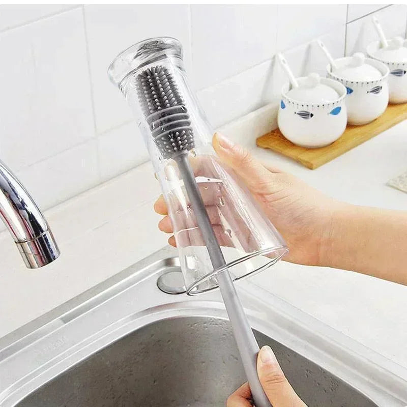 Person holding a kitchen brush with a clear handle over a sink.