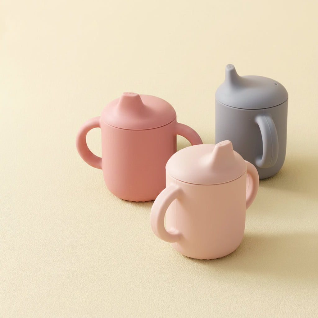 Set of colorful sippy cups on a beige background