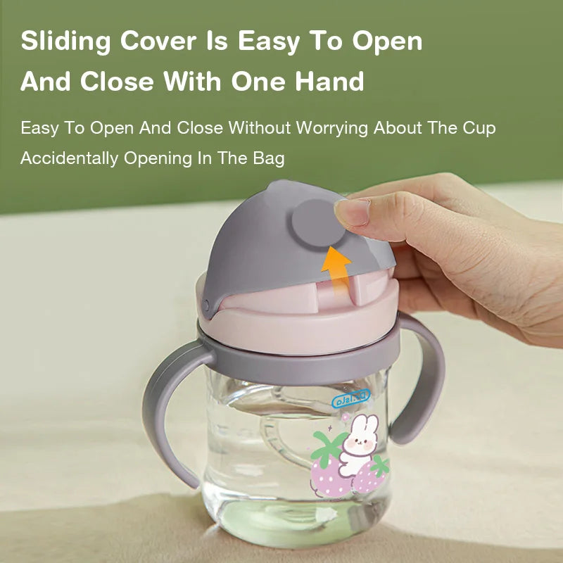 Child's sippy cup with a sliding cover being held by a hand on a light background