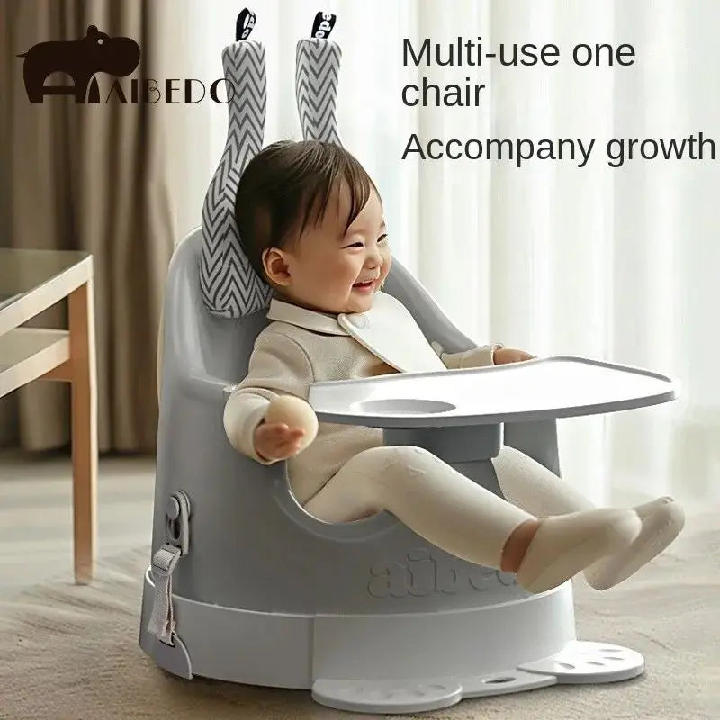 Baby sitting in a multi-use chair with Aibedo branding, smiling in a home setting.