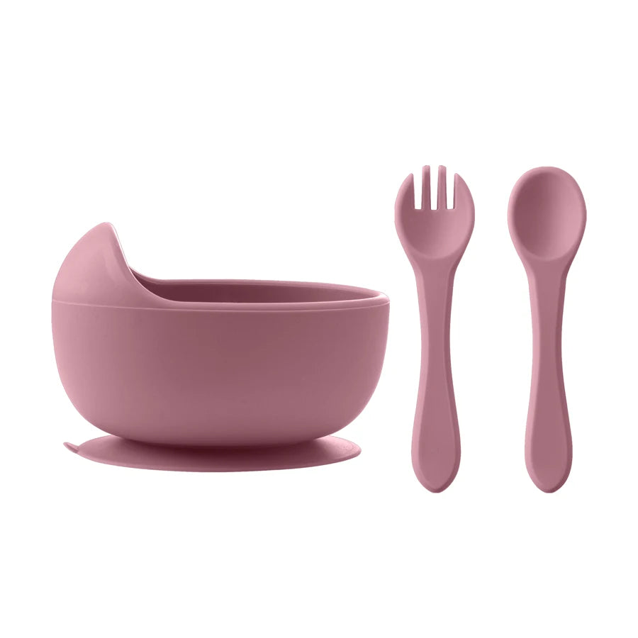 Pink children's bowl, spoon, and fork set on a white background