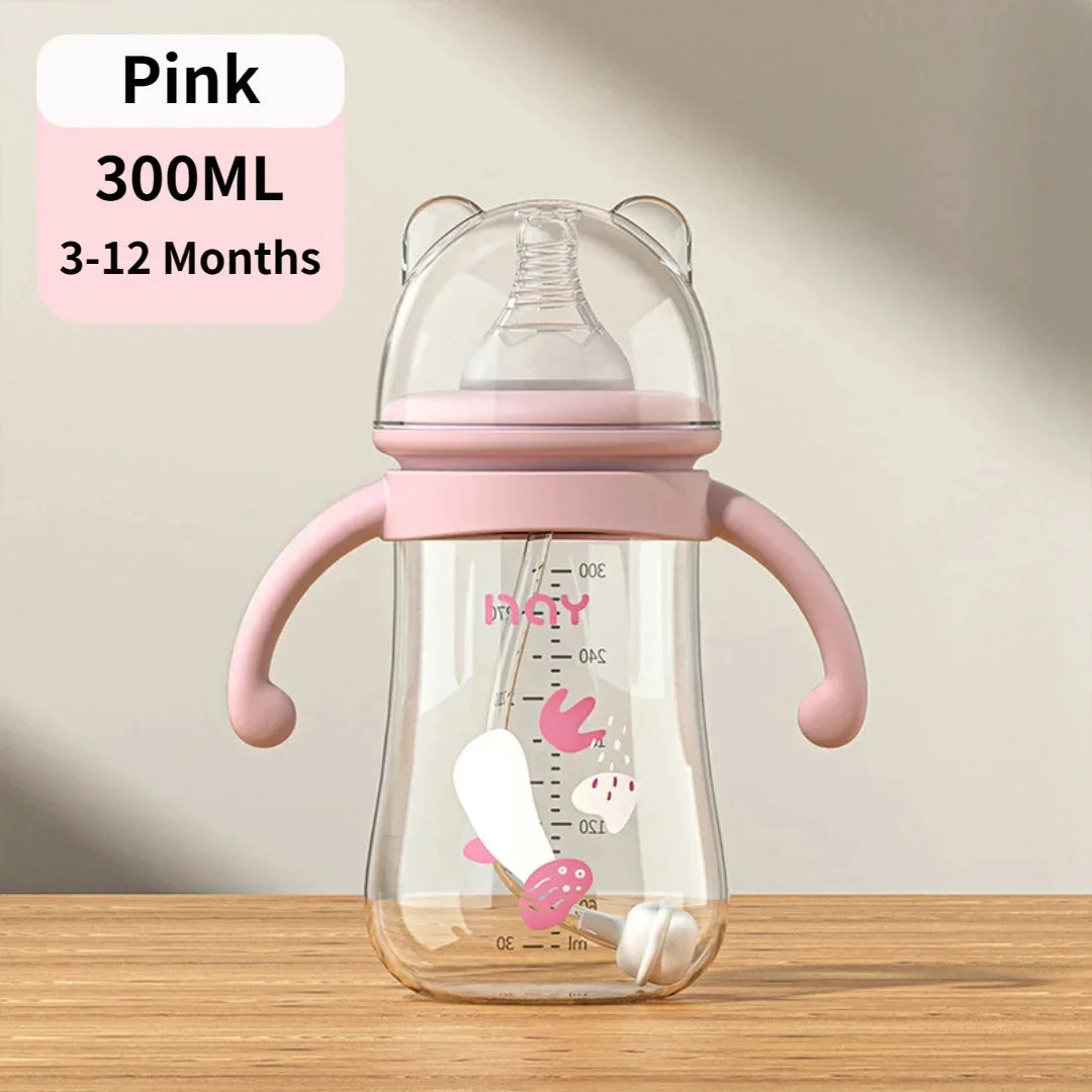 Pink baby bottle with handles on a wooden surface and beige background