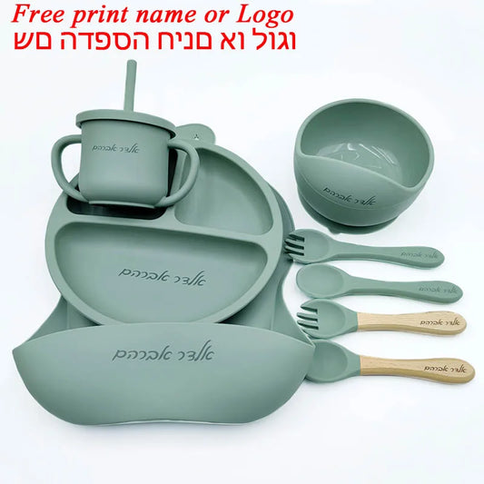 Set of green silicone dining utensils including a cup, bowl, and cutlery on a white background.